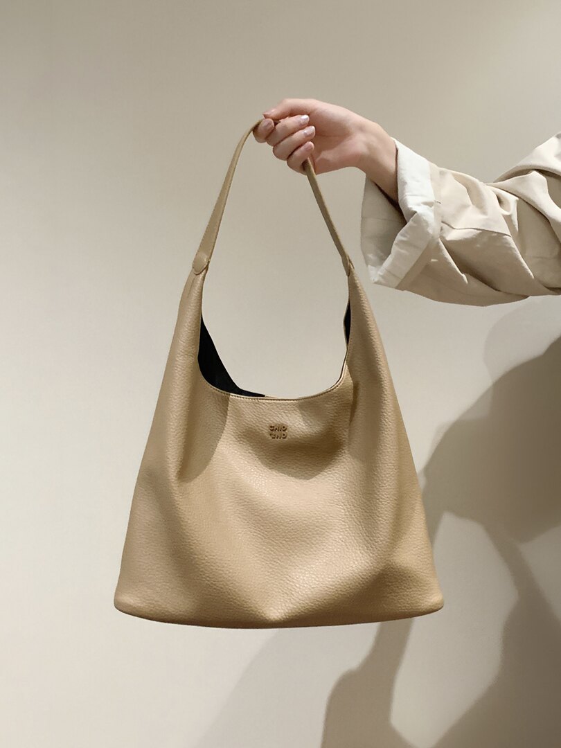 Beige leather shoulder handbag held by hand