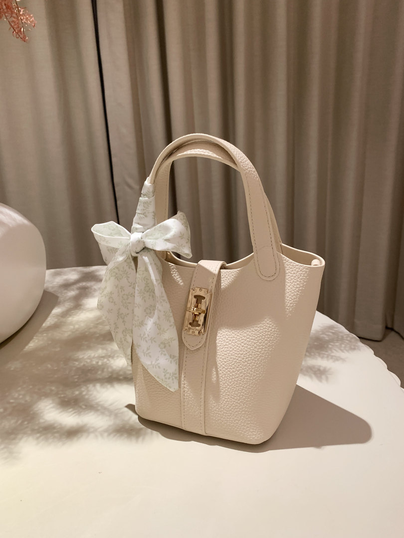 Cream textured handbag with a decorative bow and gold clasp