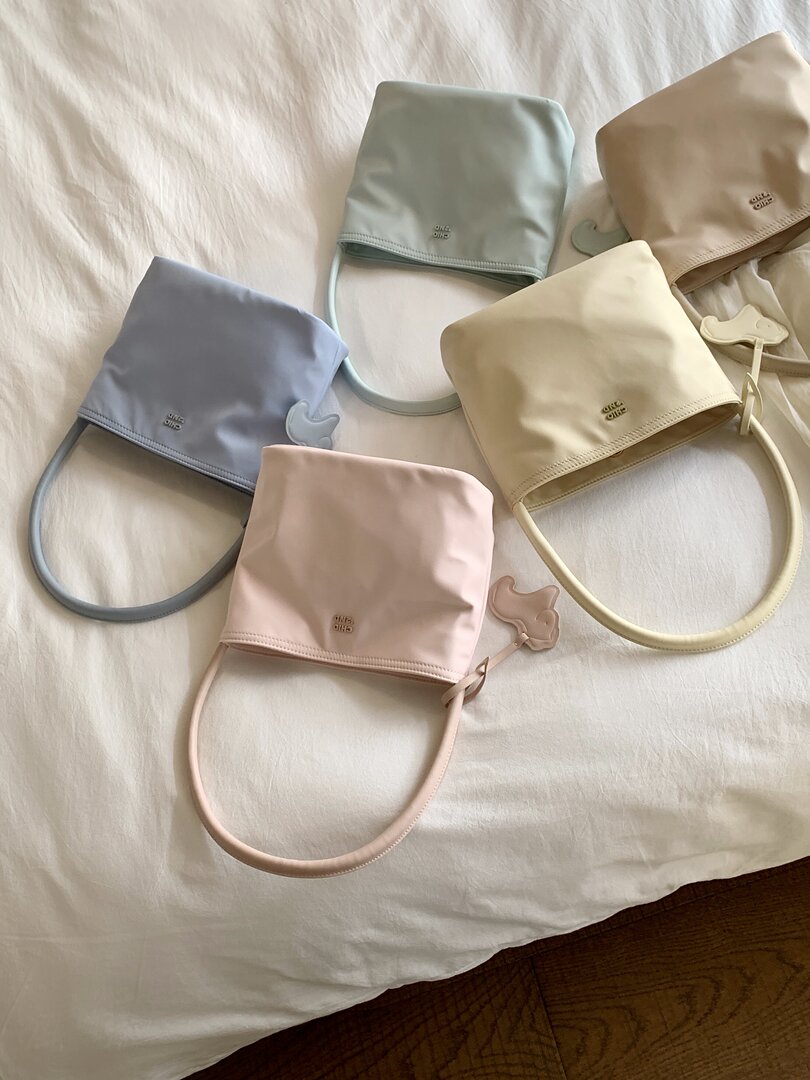 Pastel mini handbags with rounded handles laid out on white fabric