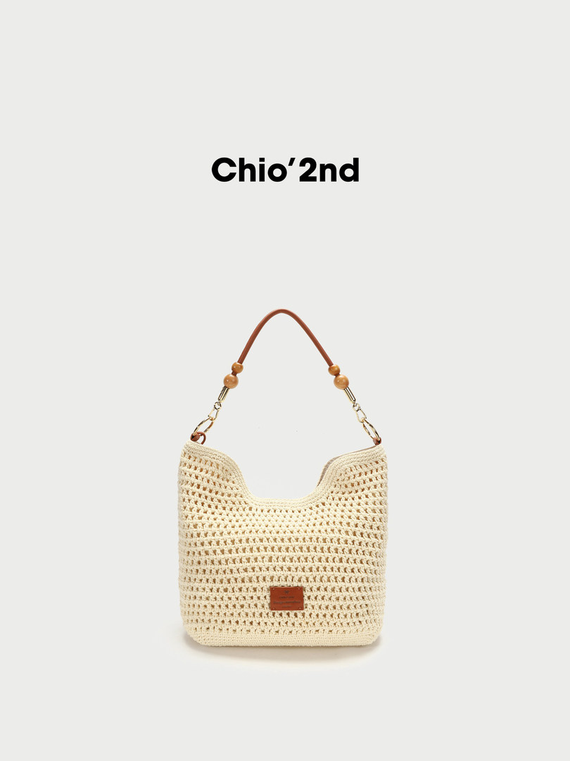 Cream crochet shoulder bag with brown strap on a white background