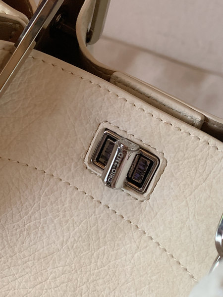Close-up of a cream leather handbag with metal clasp hardware