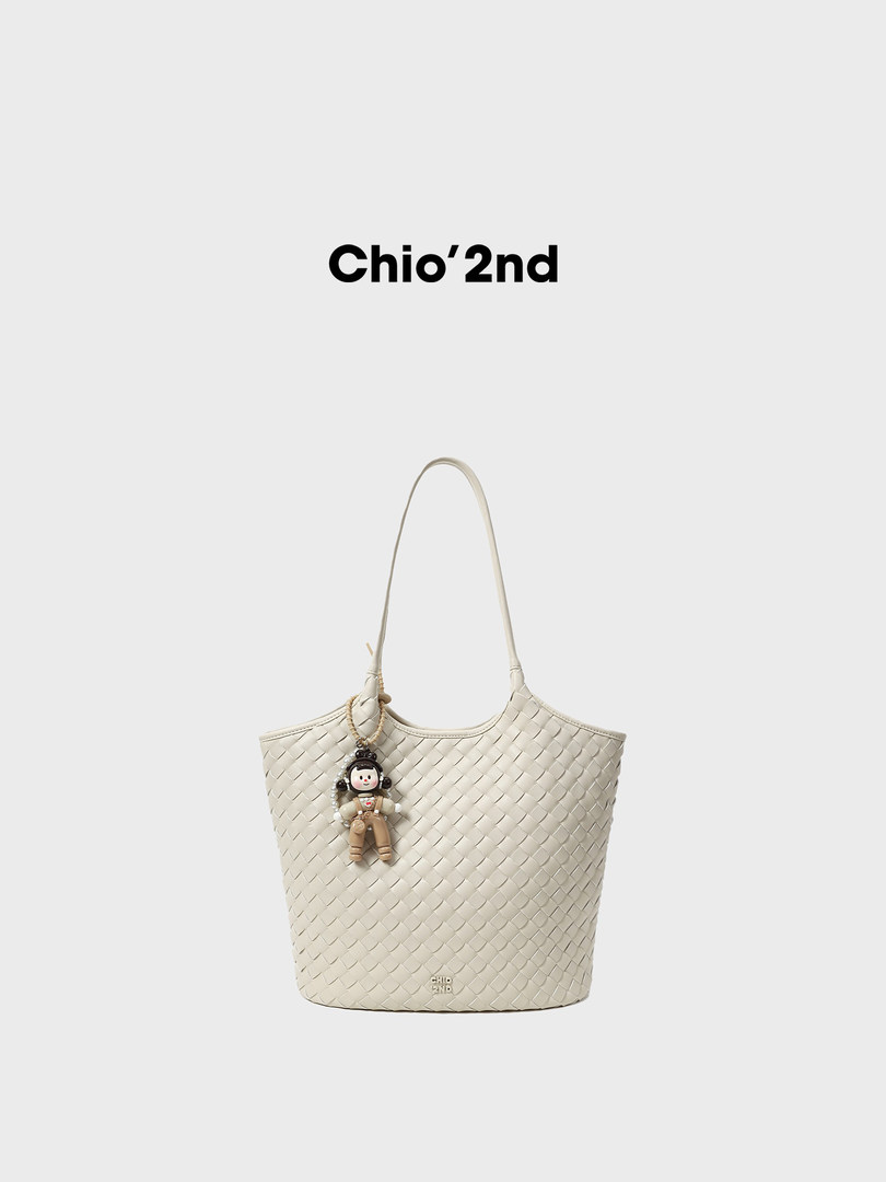 Cream woven tote handbag with charm on a plain background