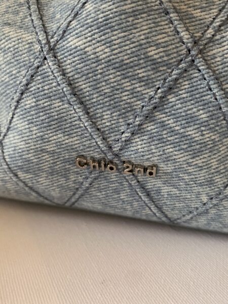Close-up of a light blue denim product with stitched pattern and metallic "chic 2nd" logo