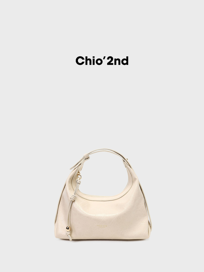 Cream leather handbag with rounded top handle and drawstring detail on a white background