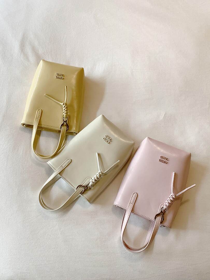 Three pastel mini handbags with straps on a light background