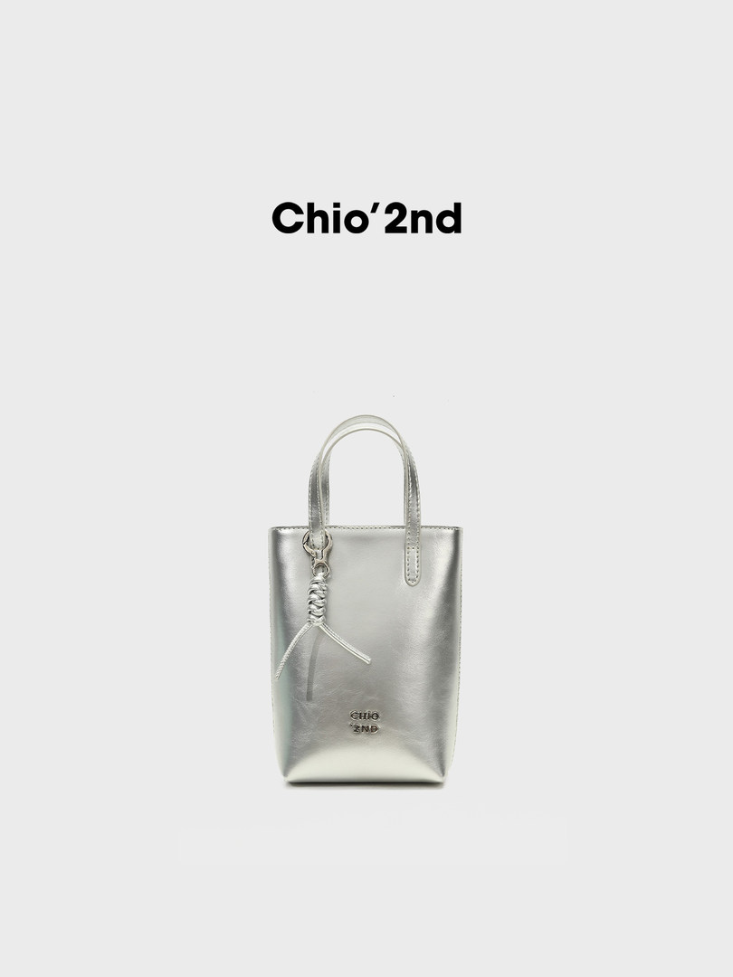 Silver metallic mini handbag with top handles and charm detail on a white background