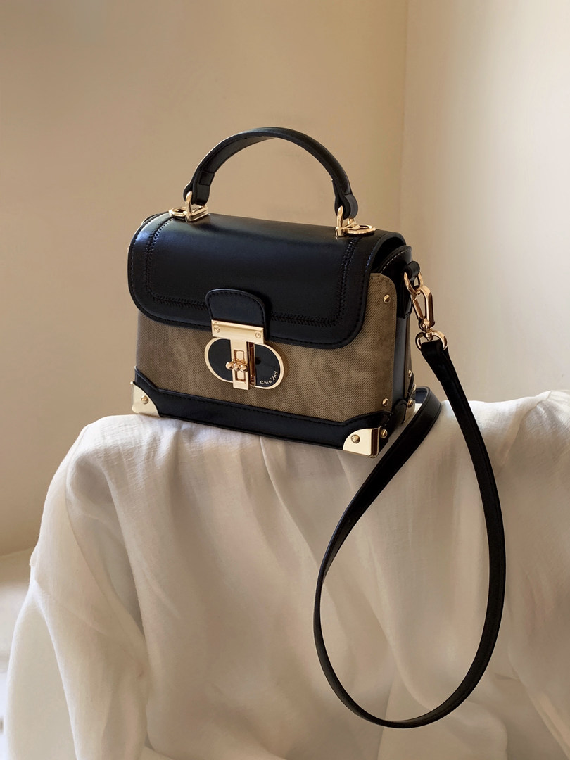 Black and tan structured handbag with gold hardware and shoulder strap