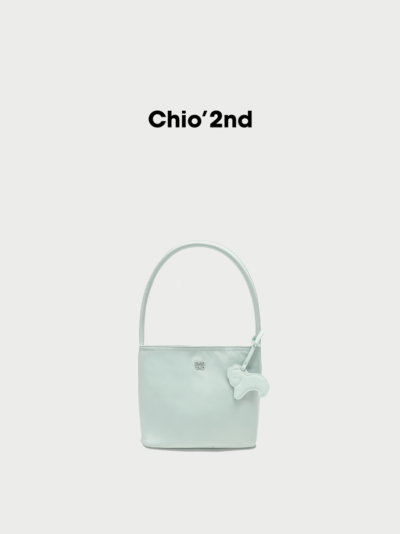 Light mint handbag with a matching charm on a plain background