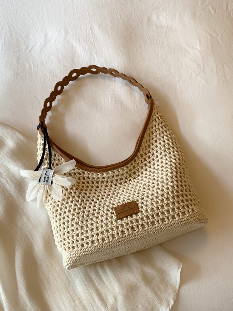Cream woven crochet handbag with brown handle and flower charm
