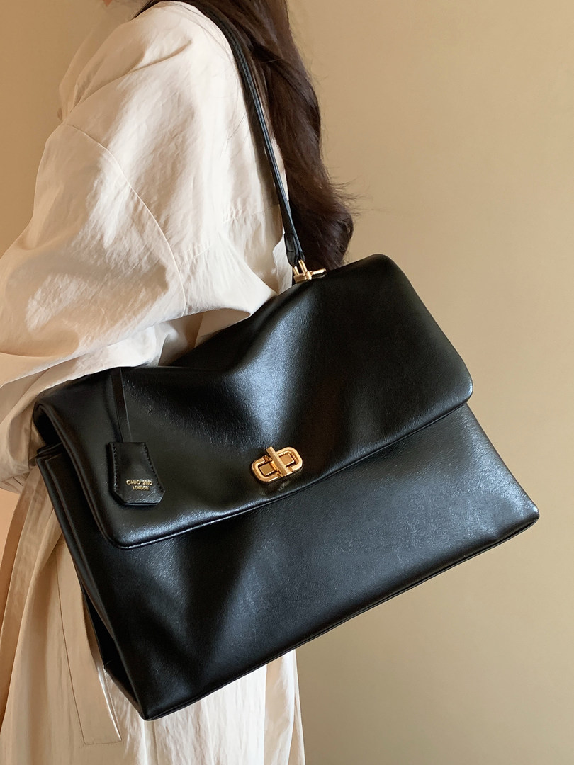 Black leather shoulder handbag worn by a model