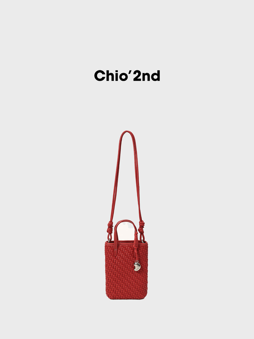 Red woven mini shoulder bag with long strap on a plain background