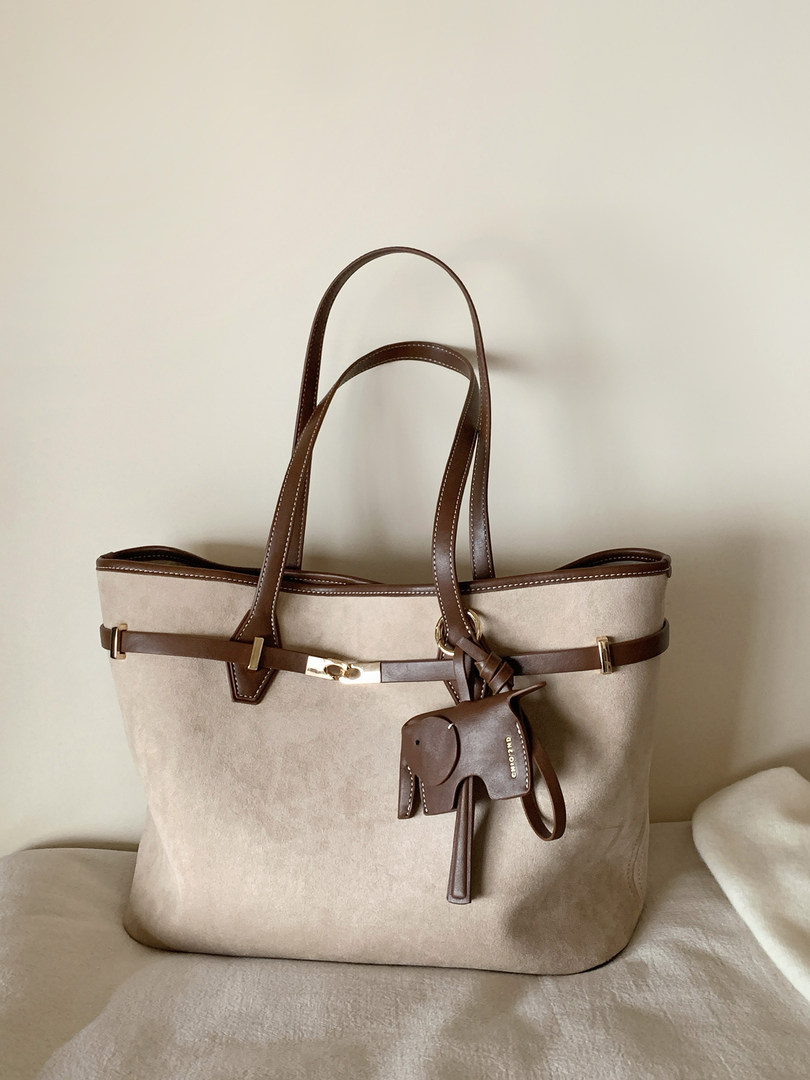 Beige tote handbag with brown leather straps and elephant charm