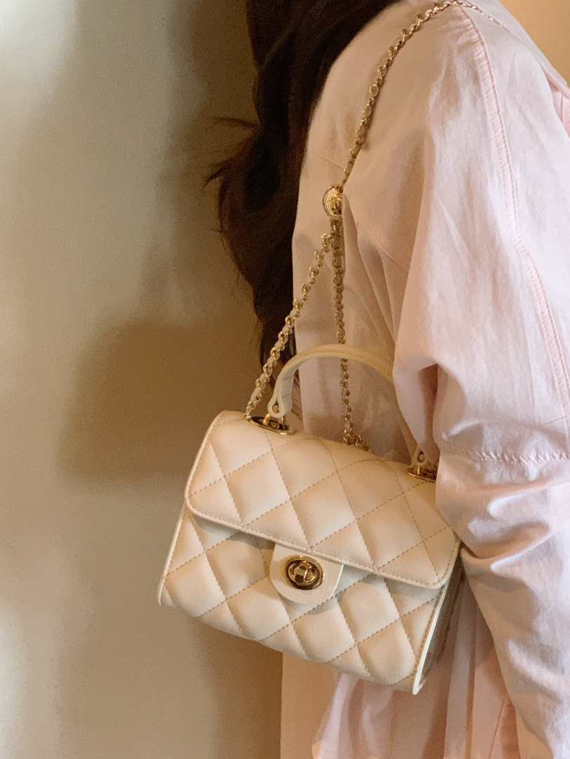 Cream quilted chain shoulder handbag worn by a model
