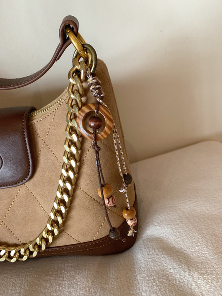 Brown and tan quilted handbag with gold chain and hanging charm
