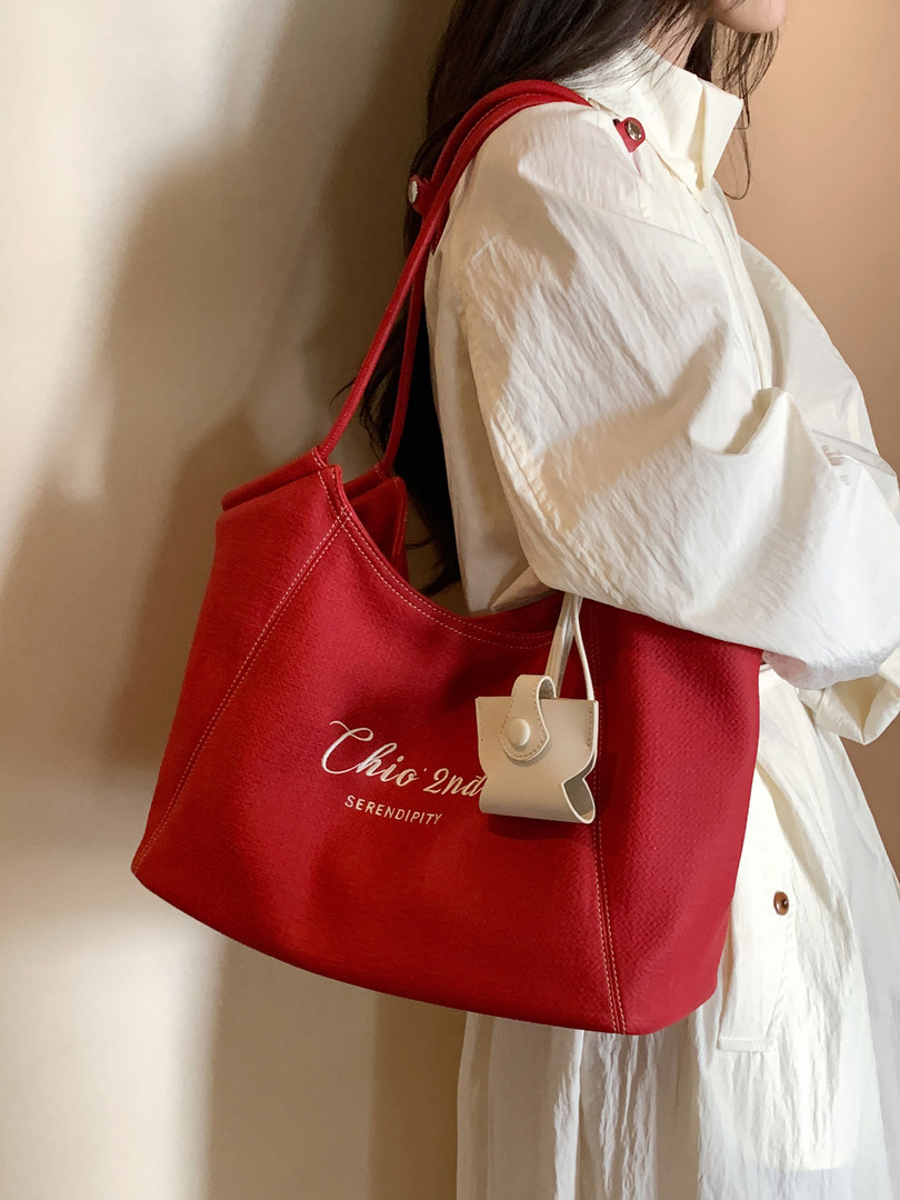 Red tote handbag worn on a model with a small charm accessory