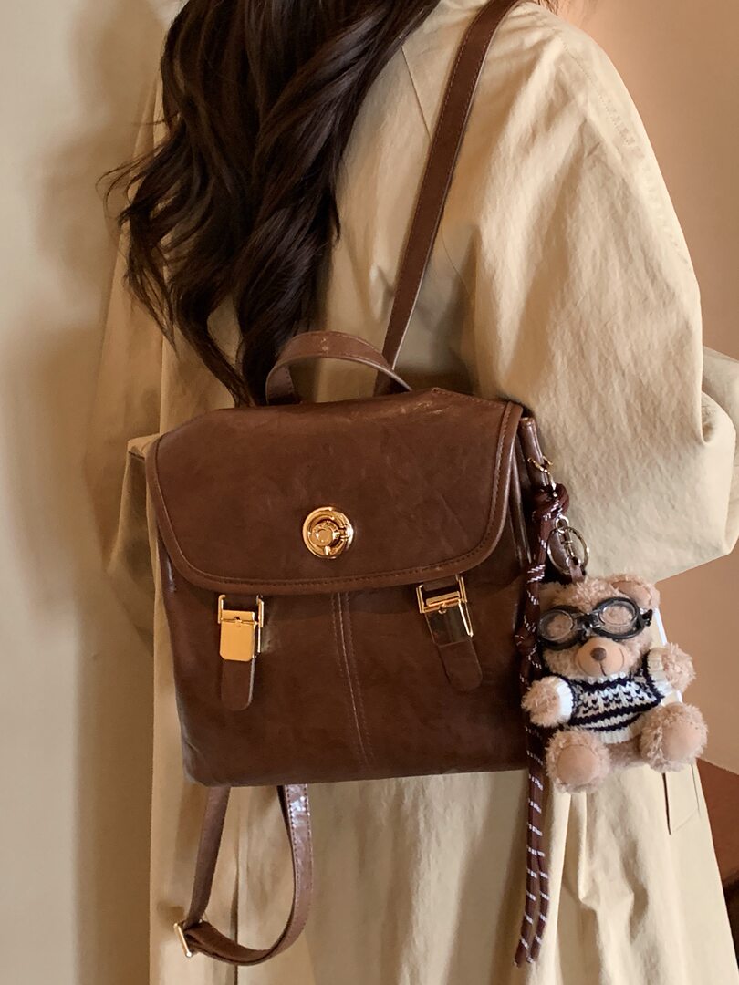 Brown leather backpack worn on a model with a teddy bear charm