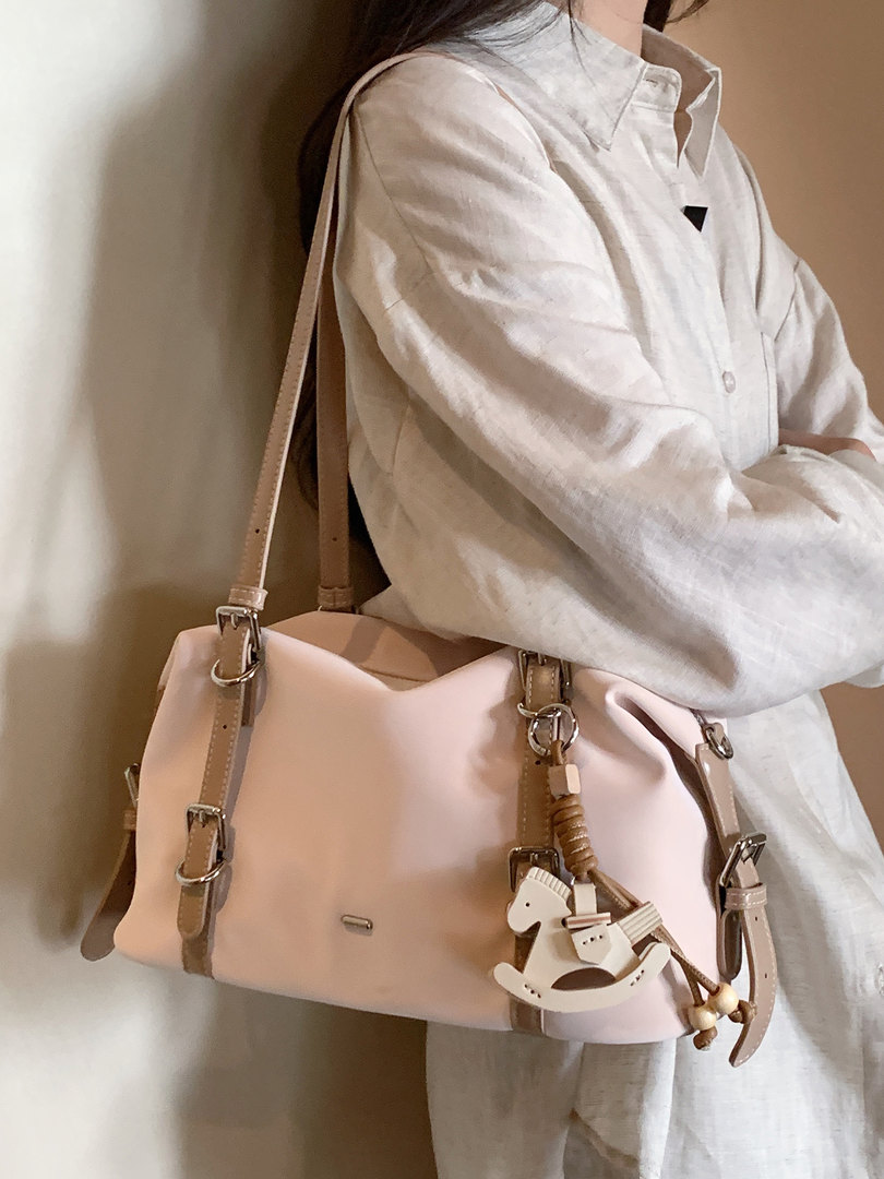Pink shoulder handbag worn by a model with charm details