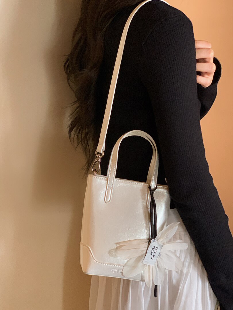 White glossy tote handbag worn crossbody on a model