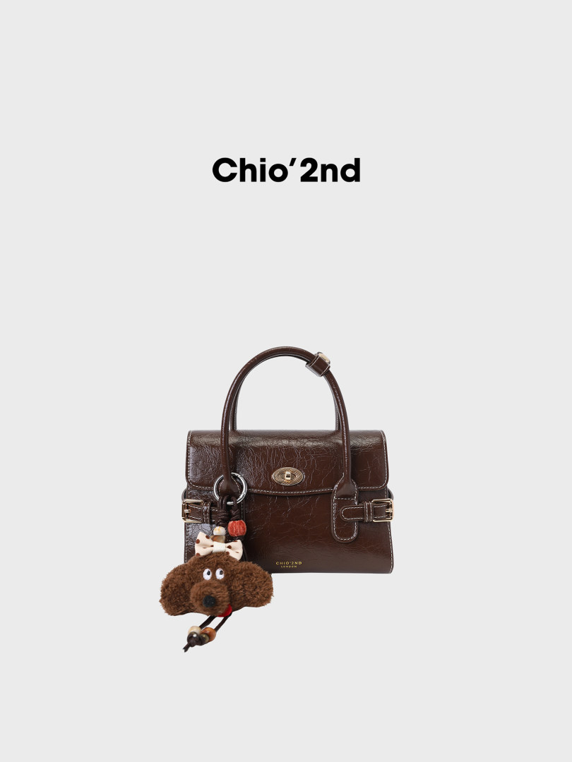 Brown leather handbag with a plush charm on a white background