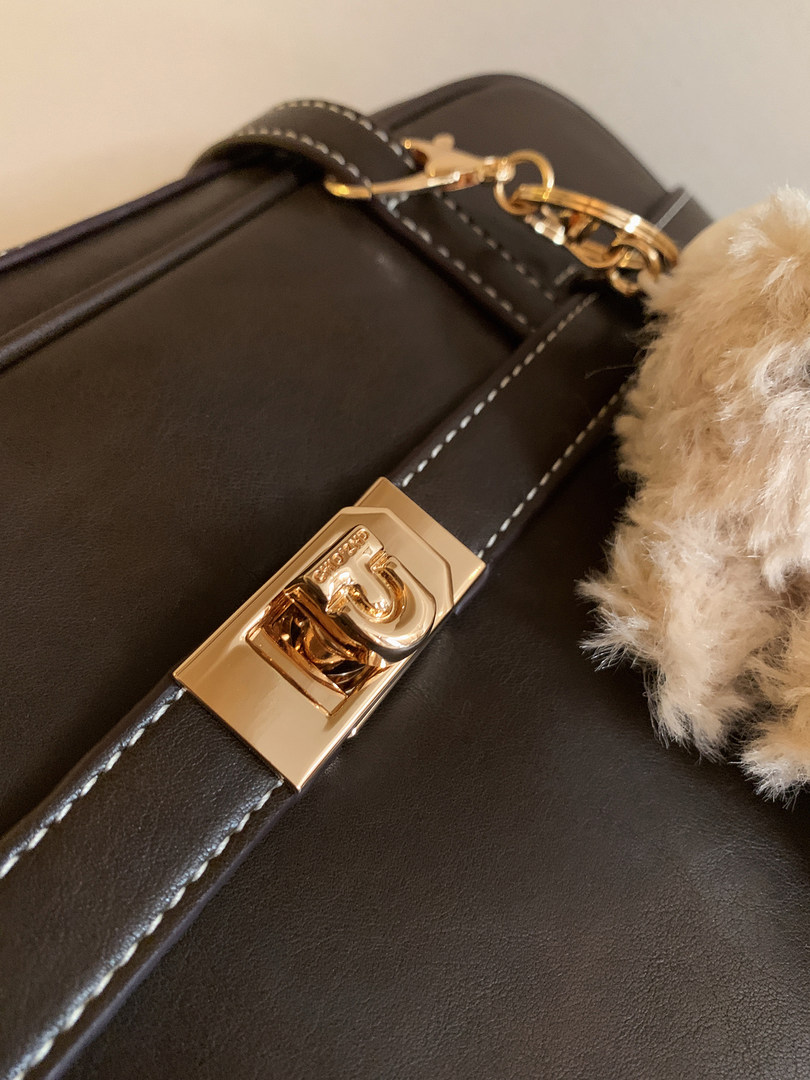 Black leather handbag with gold hardware and a fuzzy charm