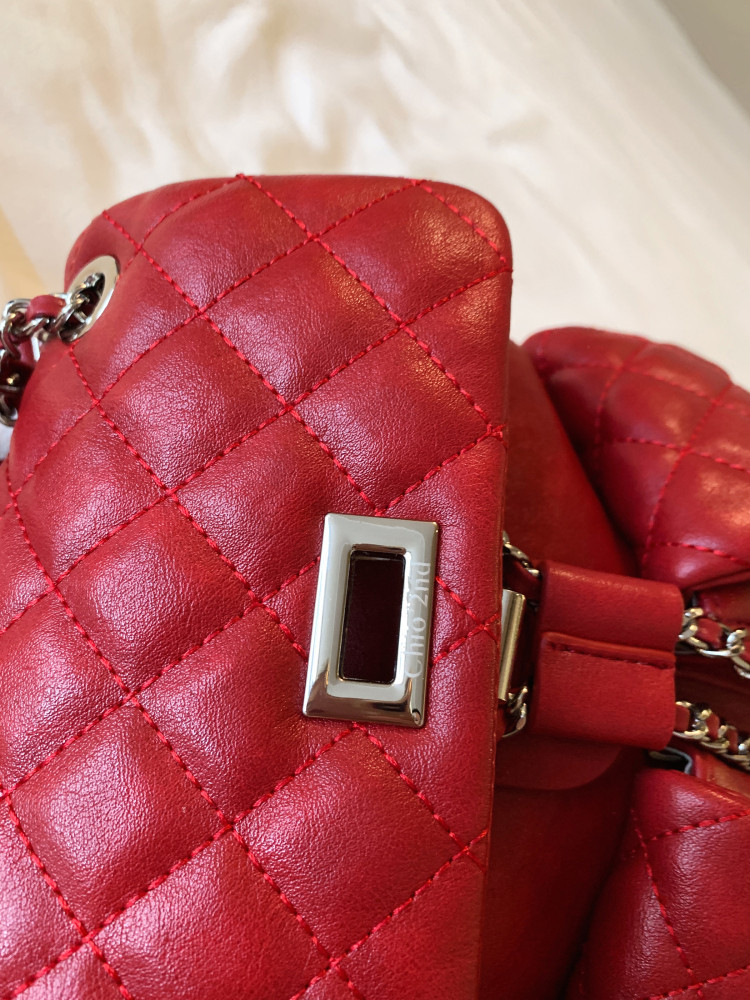 Red quilted leather handbag close-up with chain hardware and metal clasp