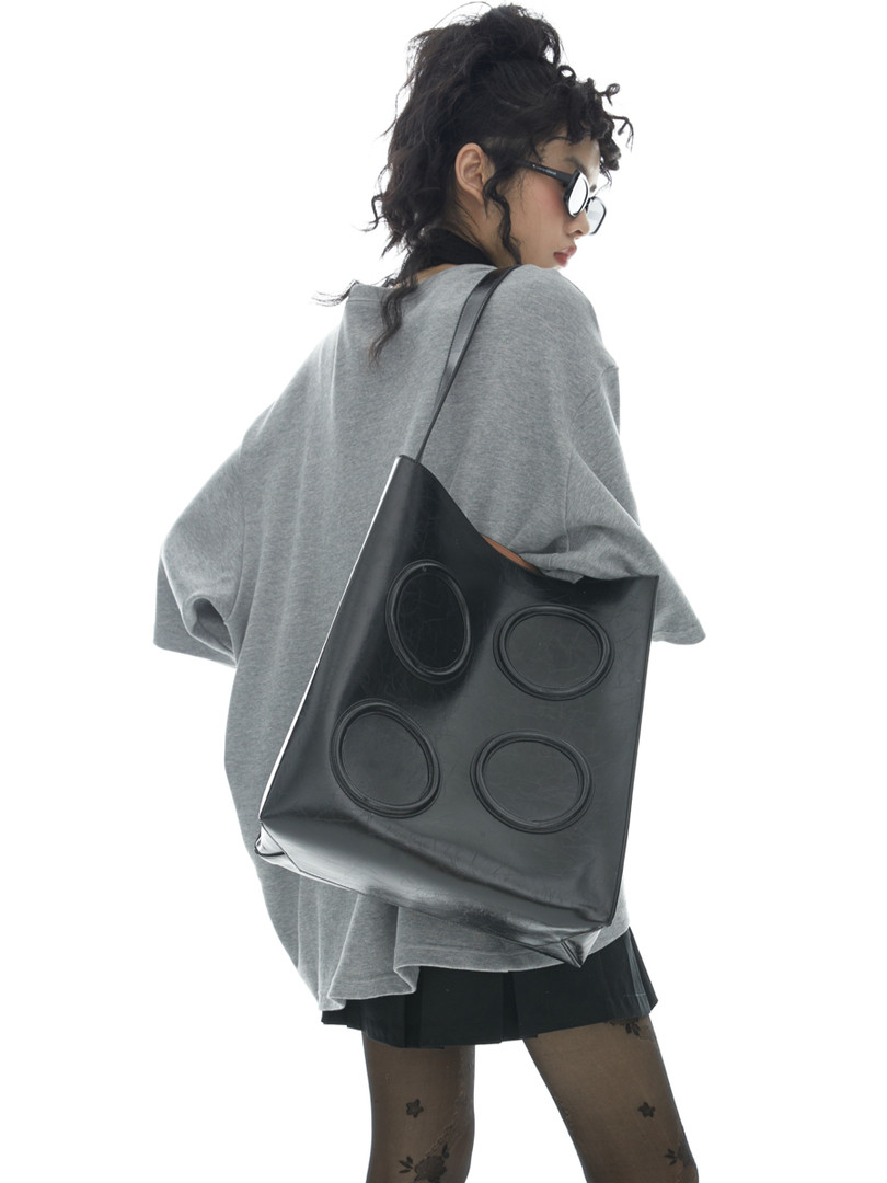 Black oversized tote bag worn by a model with a casual outfit