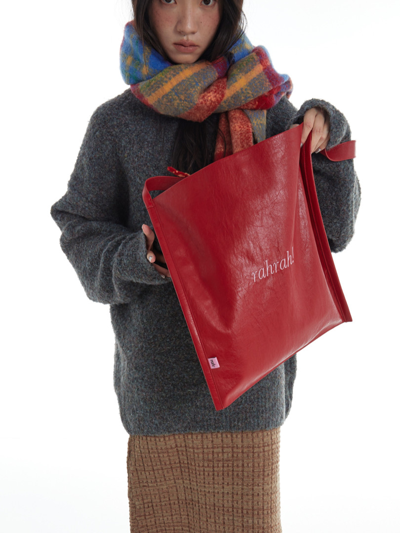 Woman holding a red leather tote bag with "rahrah." logo