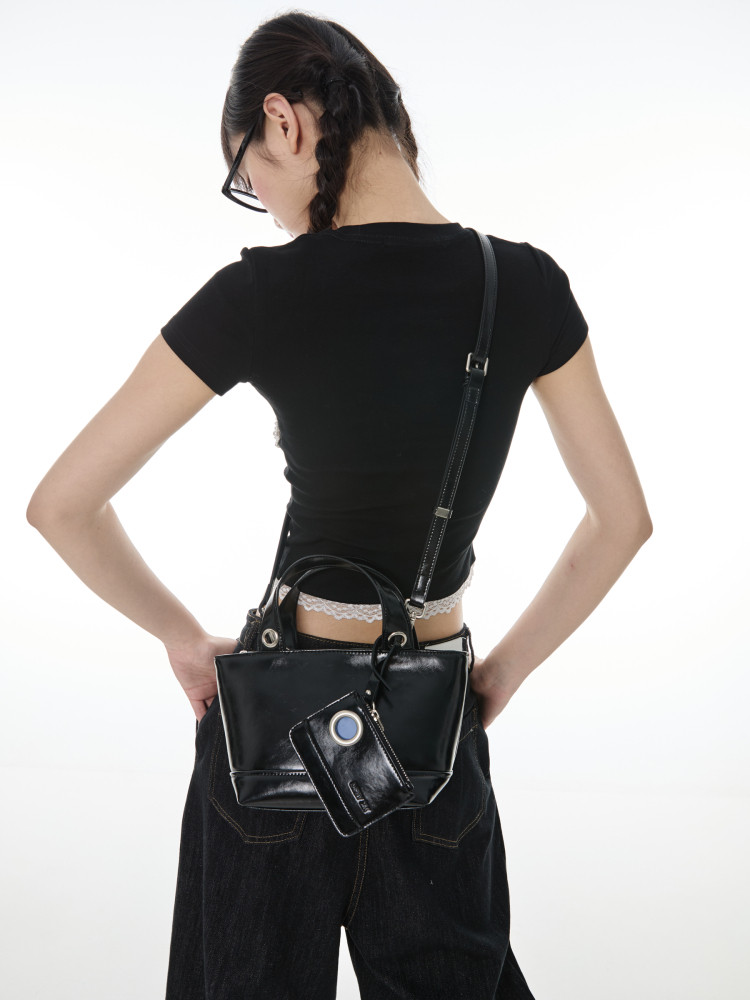 Black crossbody handbag worn on a model with matching pouch
