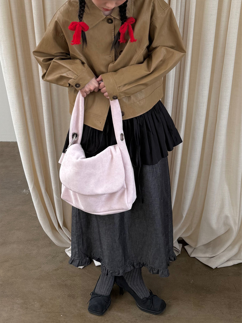 Fashion model wearing a tan jacket with a pink shoulder bag and dark skirt