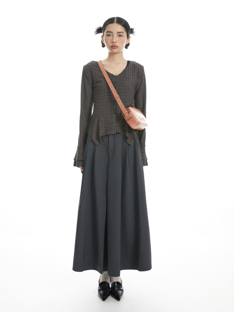 Model wearing a dark textured long-sleeve top with a long skirt and crossbody bag