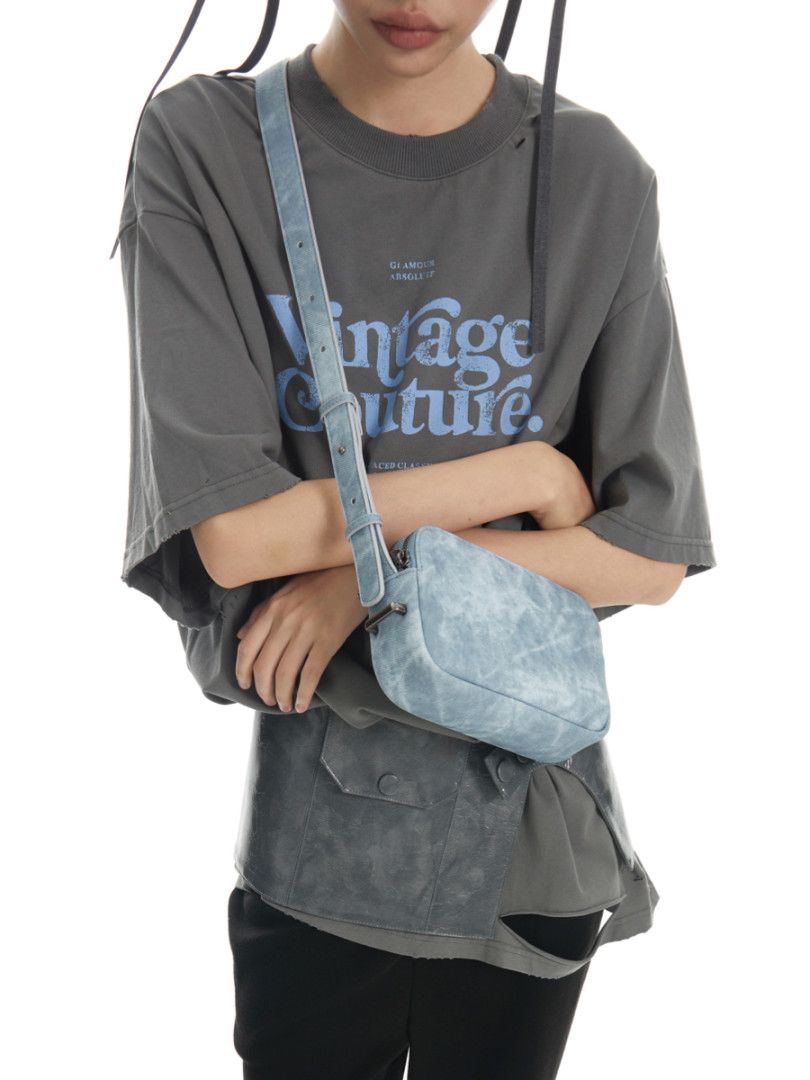 Model wearing an oversized graphic T-shirt with a light blue crossbody bag.