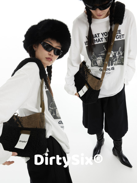 Fashion model wearing a white graphic sweatshirt, black fur hat, black pants, boots, and a crossbody bag
