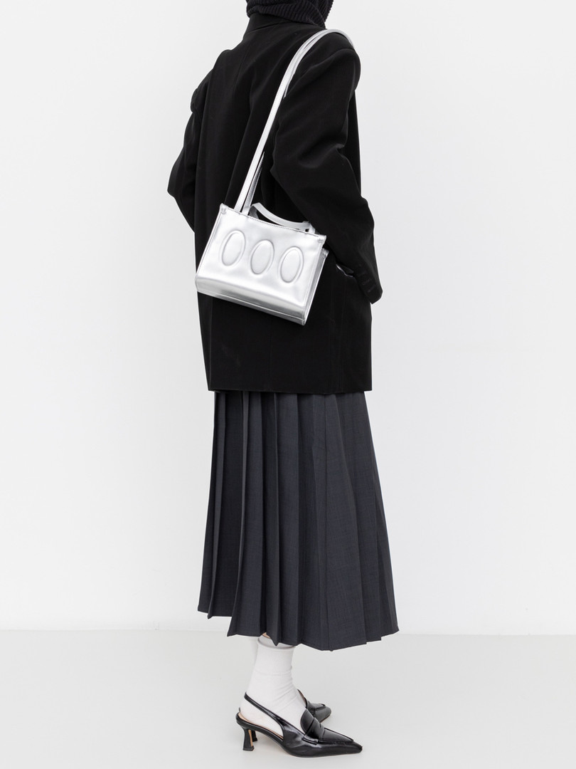 Model wearing a black outfit with a silver shoulder bag and heels