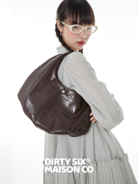 Brown leather shoulder bag worn by a model