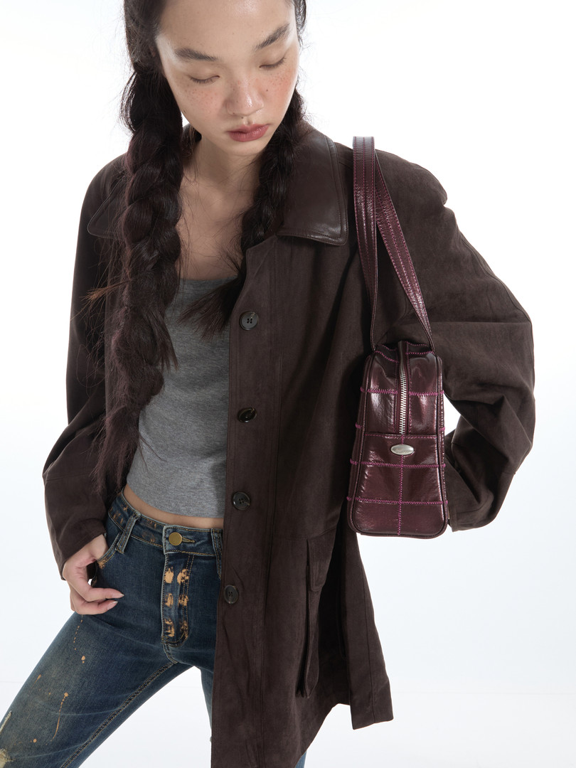 Model wearing a dark brown jacket with jeans and a burgundy shoulder bag