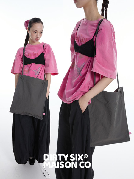 Models wearing a pink oversized graphic T-shirt with a gray shoulder tote bag