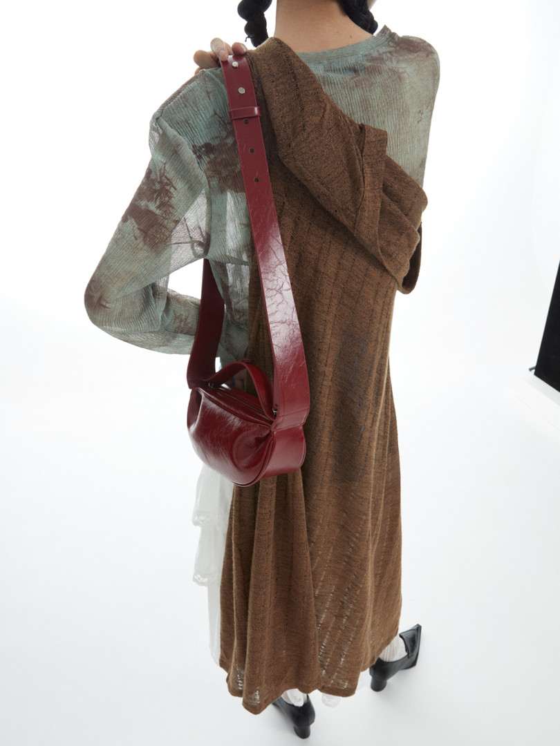 Model wearing a long layered dress with a red crossbody bag
