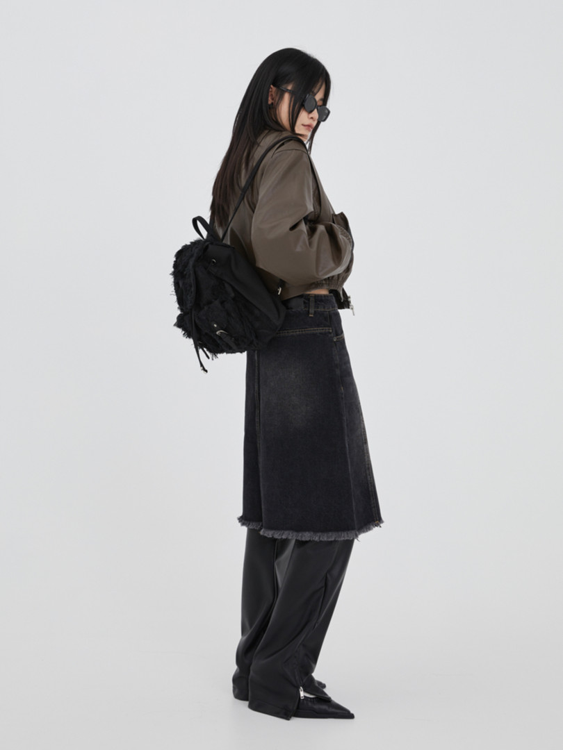 Model wearing a dark street-style outfit with a black backpack