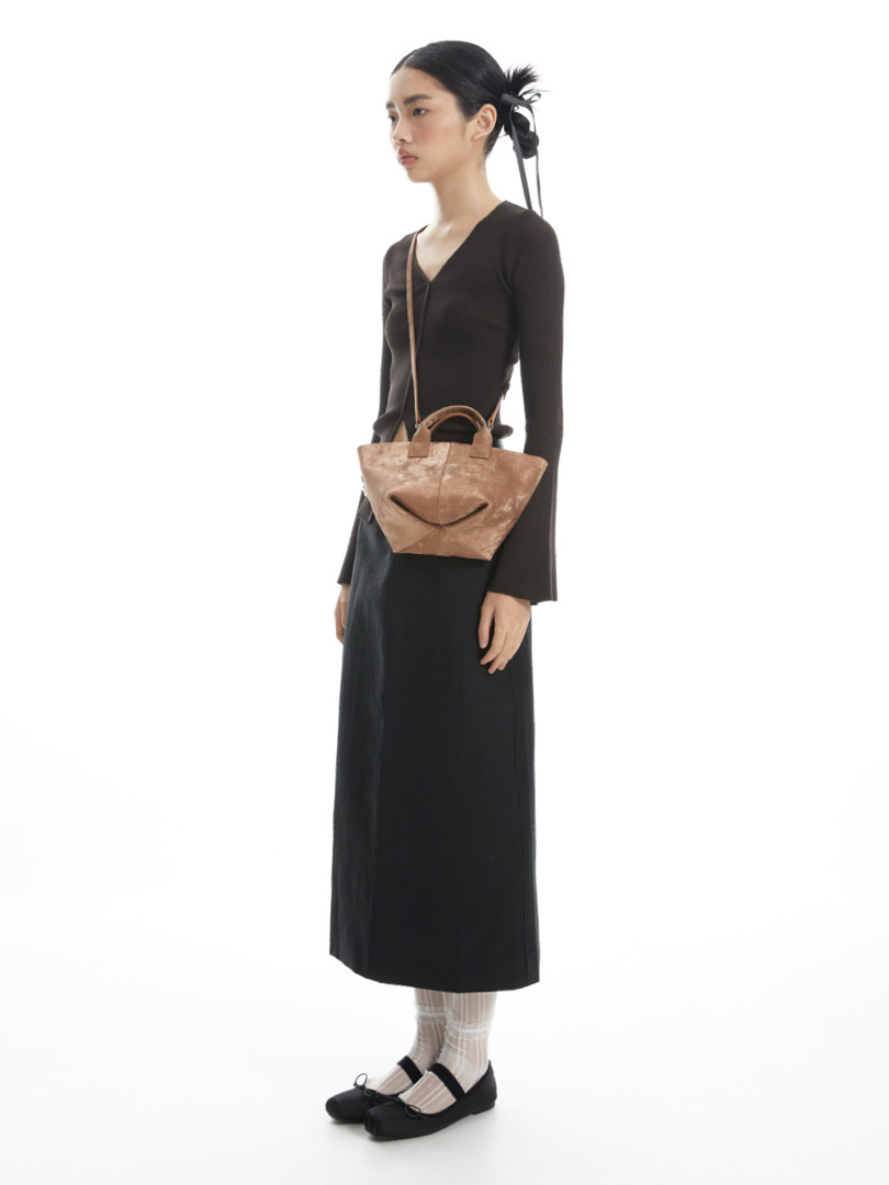 Fashion model wearing a long black dress with a brown crossbody bag