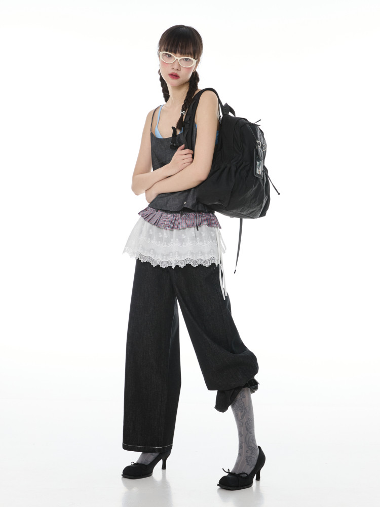 Fashion model wearing a black backpack and layered edgy outfit on a white background