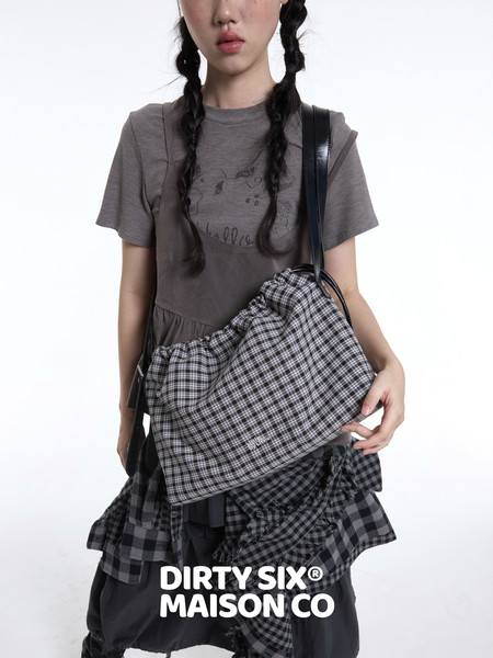 Model wearing a gray layered outfit with a plaid shoulder bag