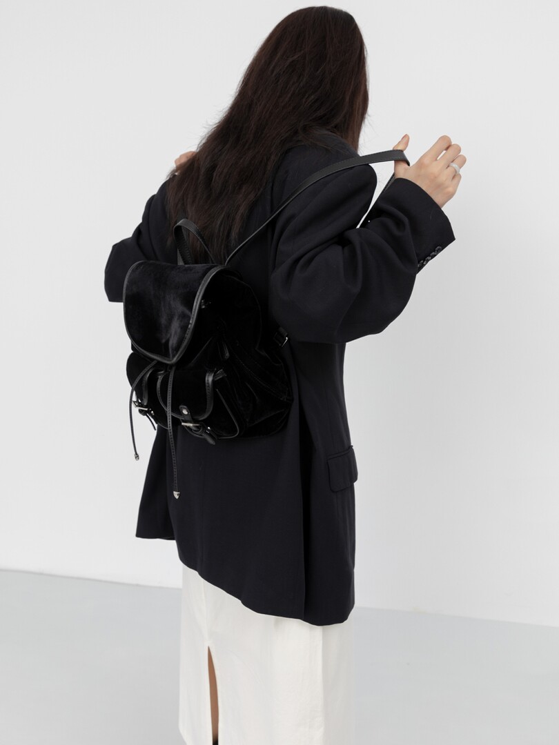 Black backpack worn on a model with a black blazer