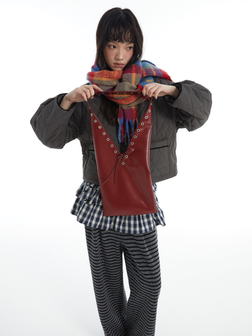 Red leather handbag held by a model in a layered outfit