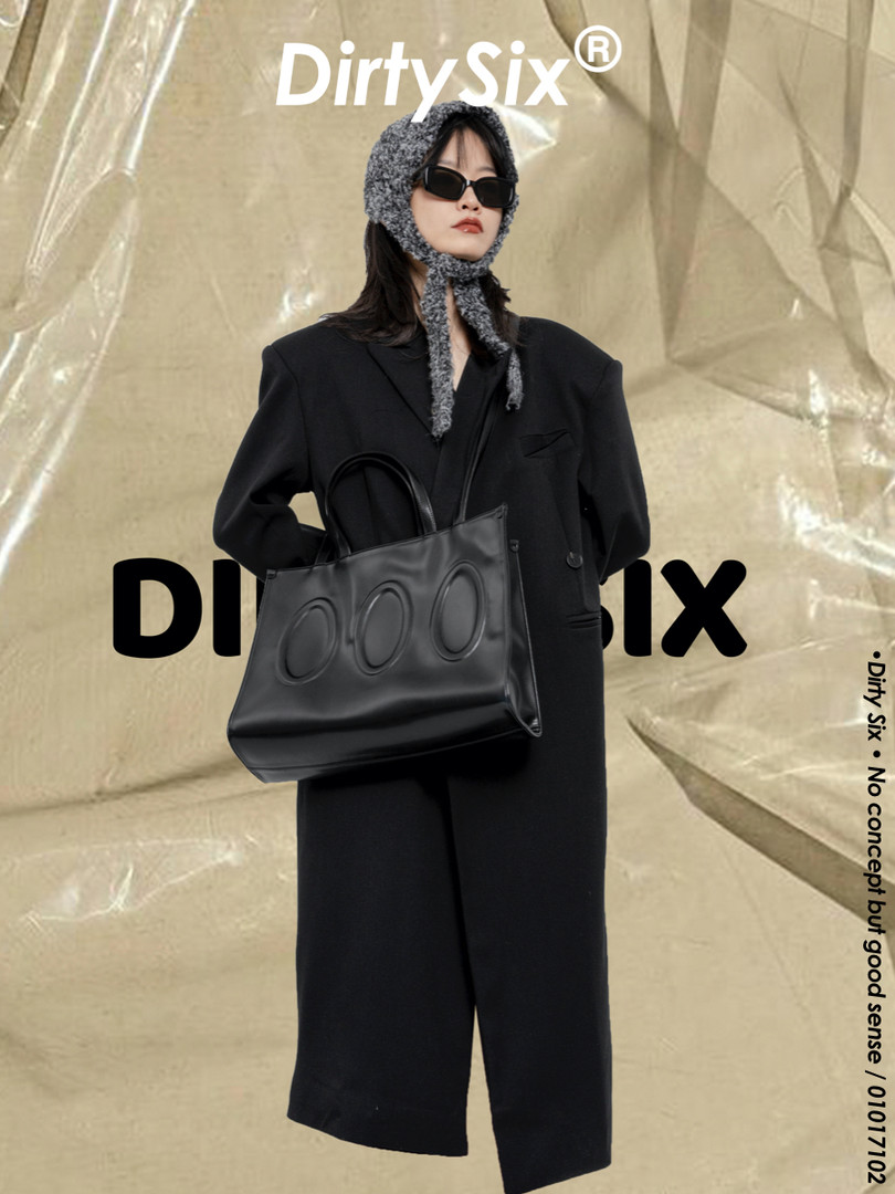 Model wearing a black oversized coat and carrying a black tote bag