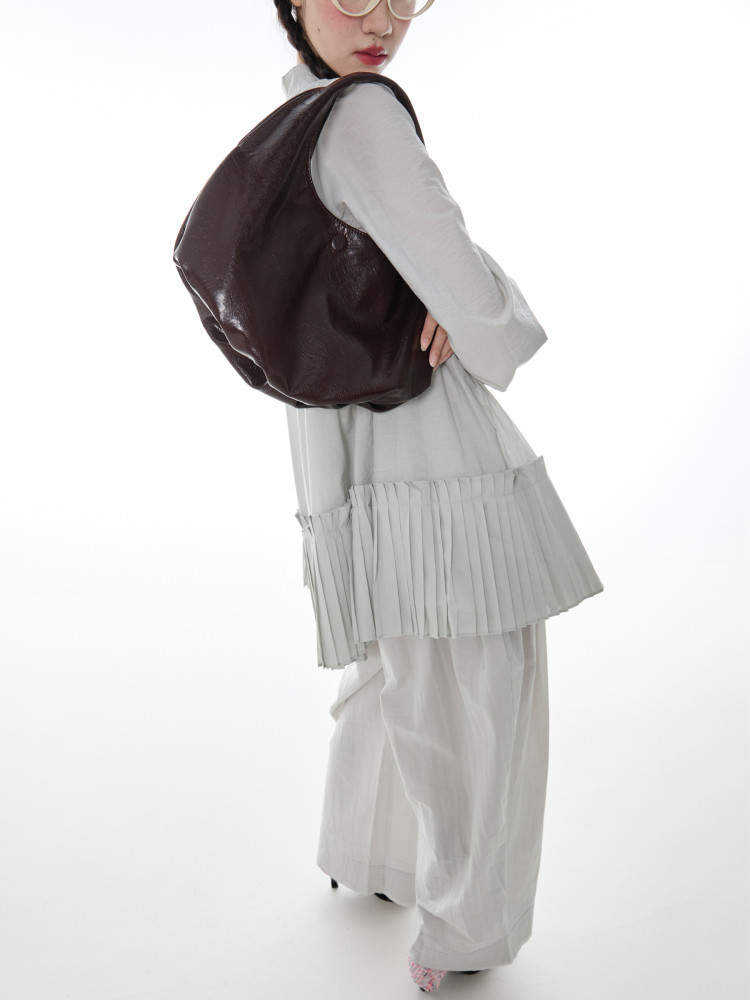 Model wearing a large dark brown leather shoulder bag with a light outfit