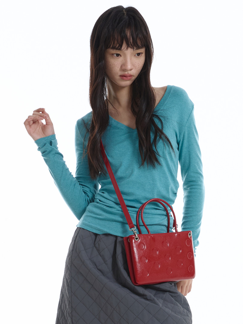 Red glossy handbag worn crossbody by a model
