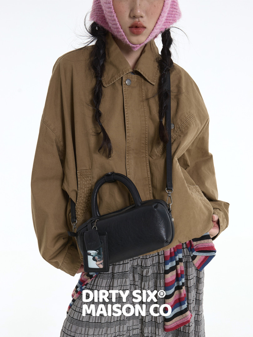 Model wearing a brown jacket with a black leather handbag