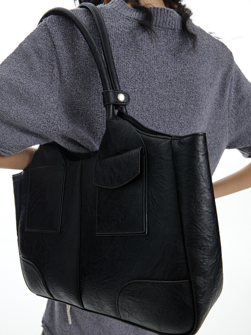 Black leather tote bag worn by a model