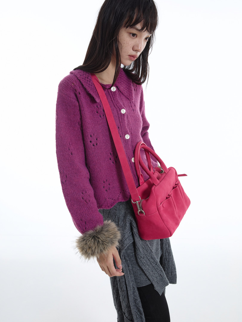 Model wearing a purple knit cardigan with a pink shoulder bag