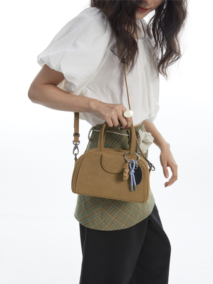Tan crossbody handbag worn by a model